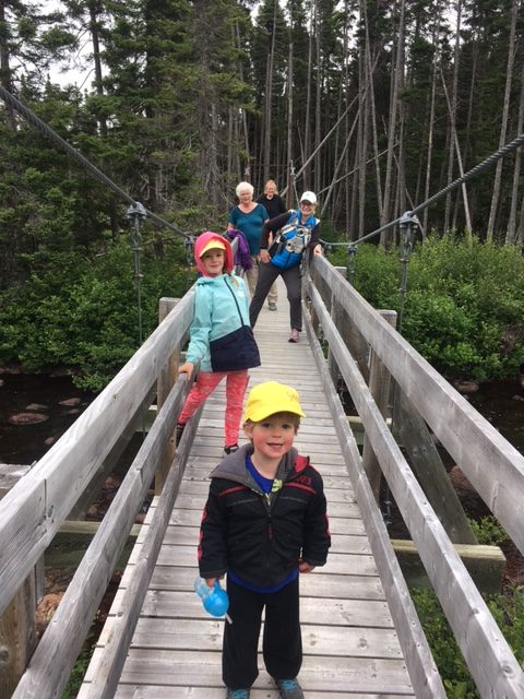 A family pauses for a picture on a suspension bridge.